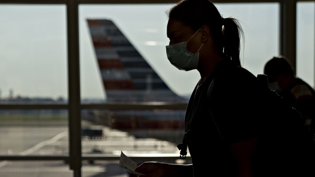 A traveler wearing a protective mask walks past an American Airlines Group Inc. plane tail fin at Ronald Reagan National Airport (DCA) in Arlington, Virginia, U.S., on Tuesday, June 9, 2020.