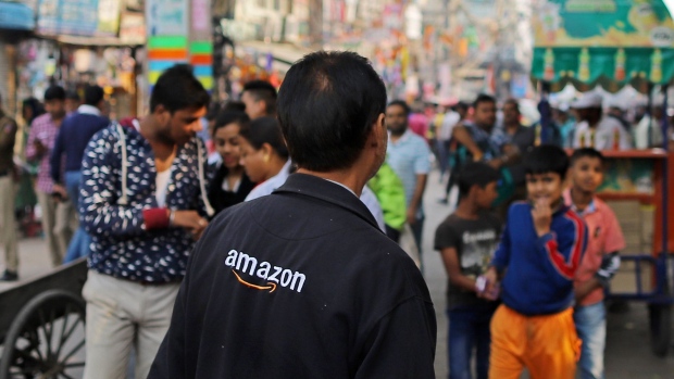 A vendor wears a jacket featuring the logo for Amazon.com Inc. at Sadar Bazaar in New Delhi, India, on Wednesday, Nov. 20, 2019. In the heart of New Delhi's largest wholesale bazaar, merchants who normally compete with each other have united against a common enemy. The sit-in, which created more chaos than usual among the rickshaws, motorbikes and ox-carts plying the market road, was one of as many as 700 protests against Amazon.com Inc. and Walmart Inc. -- owner of local e-commerce leader Flipkart -- that organizers say took place at bazaars across India on a recent Wednesday.