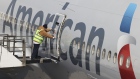 A worker closes the door on an American Airlines Group Inc. plane at a gate in Terminal 8 at John F. Kennedy International Airport (JFK) in New York, U.S., on Friday, March 26, 2021. The TSA screened more than 1.3 million people both Friday and Sunday, setting a new high since the coronavirus outbreak devastated travel a year ago. Airlines say they believe the numbers are heading up, with more people booking flights for spring and summer, reports the Associated Press. Photographer: Angus Mordant/Bloomberg