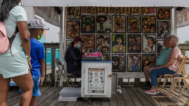 A caricature artist draws the image of a couple while customers wait in line at a vendor stall at Broadway at the Beach in Myrtle Beach, South Carolina. Photographer: Micah Green/Bloomberg