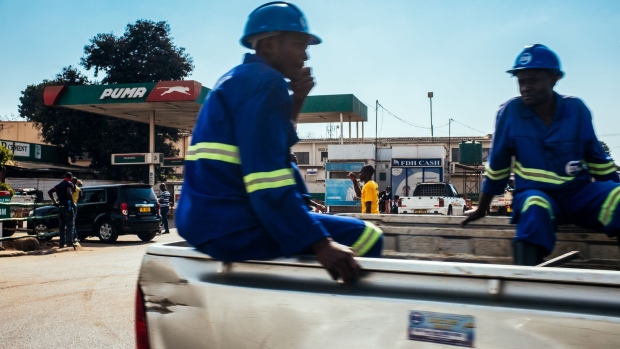 Construction workers ride in the back of a pickup truck past a Puma Energy Holdings Pte. Ltd. gas station Lilongwe, Malawi, on Tuesday, June 26 2018. The diversification of the agriculture-reliant economy is a top priority, Malawian President Peter Mutharika said in an interview on Monday.
