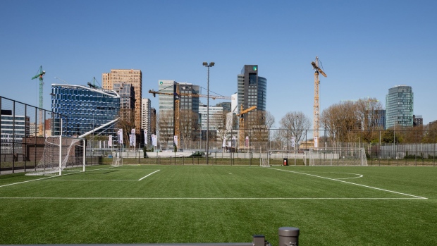 The Arcadis NV headquarters, second left, and the ABN Amro NV headquarter office complex stand beyond a soccer field in the Zuidas financial district in Amsterdam, Netherlands, on Wednesday, April 10, 2019. The Netherlands will become the first country with a AAA credit rating to issue a green bond with the sale of a 20-year security next month. Photograper: Marlene Awaad/Bloomberg Photographer: Marlene Awaad/Bloomberg