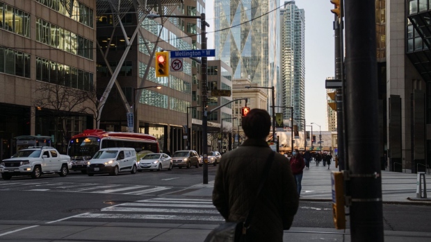 A pedestrian waits to cross at the corner of Bay Street and Wellington Street West in the financial district of Toronto, Ontario, Canada, on Thursday, March 25, 2021. Premier Doug Ford said further lockdowns could happen as a government agency that tracks hospitalizations reported the biggest single-day jump in admissions of patients to intensive care since the pandemic began, CBC reports. Photographer: Galit Rodan/Bloomberg