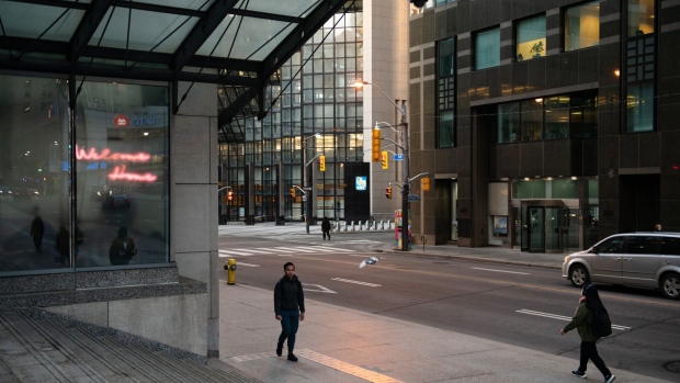 Pedestrians walk along Bay Street in the financial district of Toronto on March 25.