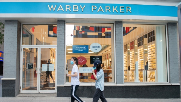 NEW YORK, NEW YORK - AUGUST 08: People wearing masks walk past Warby Parker near Rockefeller Center as the city continues Phase 4 of re-opening following restrictions imposed to slow the spread of coronavirus on August 08, 2020 in New York City