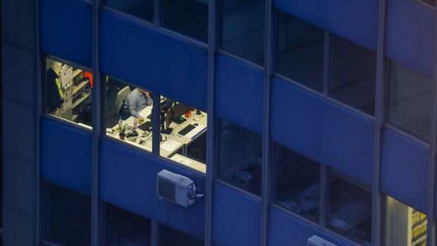 A city worker sits at a desk in illuminated office in the financial district in Frankfurt, Germany. Photographer: Alex Kraus/Bloomberg