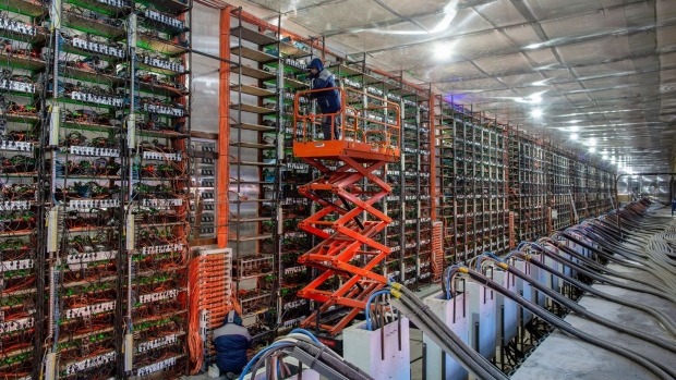 An engineer on a cherry picker adjusts mining rigs at the CryptoUniverse cryptocurrency mining farm in Nadvoitsy, Russia, on Thursday, March 18, 2021. The rise of Bitcoin and other cryptocurrencies has prompted the greatest push yet among central banks to develop their own digital currencies. Photographer: Andrey Rudakov/Bloomberg