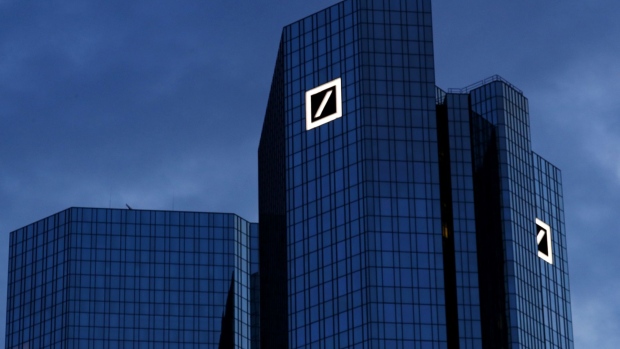 The Deutsche Bank AG logo and a few office windows sit illuminated at the bank's headquarters in the financial district in Frankfurt.