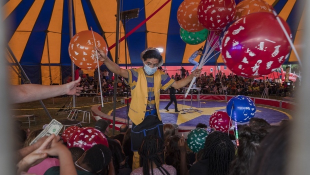 A clown wearing a protective mask sells balloons in-between acts during a performance of the Zerbini Family Circus in Sumter, South Carolina, U.S., on Friday, April 30, 2021. Governor McMaster said government-mandated mask wearing and other Covid-19 restrictions need to end in South Carolina, according to The Post and Courier. Photographer: Micah Green/Bloomberg