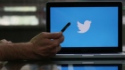 An Apple Inc. iPhone 6 smartphone is held as a laptop screen shows the Twitter Inc. logo in this arranged photograph taken in London, U.K Photographer: Chris Ratcliffe/Bloomberg