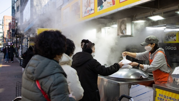 A customer wearing a protective face mask pays for her purchase at a dumpling store in Mangwon Market in Seoul, South Korea, on Tuesday, Feb. 9, 2021. South Korea relaxed its social distancing rules on Monday, allowing longer opening hours for some retail businesses, as the number of new coronavirus infections declines. Photographer: SeongJoon Cho/Bloomberg