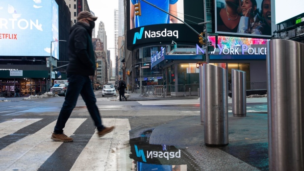 A pedestrian passes in front of the Nasdaq MarketSite in New York, U.S., on Monday, Dec. 21, 2020. Tesla Inc.'s was among the biggest drags on the S&P 500 in its first day of trading on the benchmark. Photographer: Michael Nagle/Bloomberg