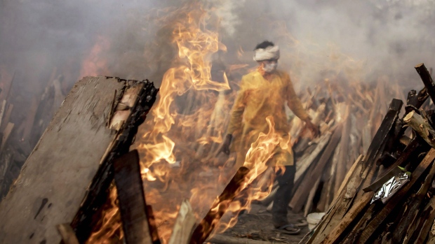 NEW DELHI, INDIA - MAY 01: A priest who works at a crematorium is seen amid burning funeral pyres of patients who died of COVID-19 on May 01, 2021 in New Delhi, India. With cases crossing 400,000 a day and with more than 3500 deaths recorded in the last 24 hours, India's Covid-19 crisis is intensifying and shows no signs of easing pressure on the country. A new wave of the pandemic has totally overwhelmed the country's healthcare services and has caused crematoriums to operate day and night as the number of victims continues to spiral out of control. (Photo by Anindito Mukherjee/Getty Images)