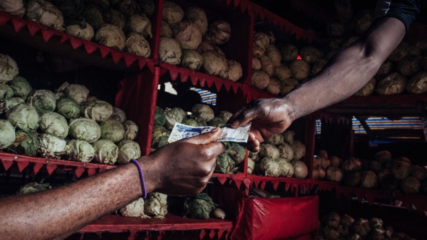 A customer hands a vendor a 500 Nigerian naira banknote for fresh produce on a stall at Utako Ultra Modern market in Abuja, Nigeria, on Wednesday, June 3, 2020. The government of Nigeria, whose revenue could be slashed by more than half this year due to the oil-price slump, finalized plans for a revised budget that keeps spending almost intact, and that will mean more borrowing. Photographer: KC Nwakalor/Bloomberg