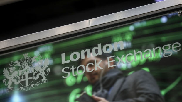 An employee sits reflected in a glass screen featuring the London Stock Exchange Group Plc's logo at their offices in London, U.K., on Thursday, Jan. 2, 2020. Stocks started the year on the front foot, building on strong gains for many asset classes in 2019 as investors cheered the latest policy move by Chinas central bank to support its economy. Photographer: Bloomberg/Bloomberg
