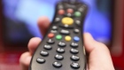 A man holds a television remote control