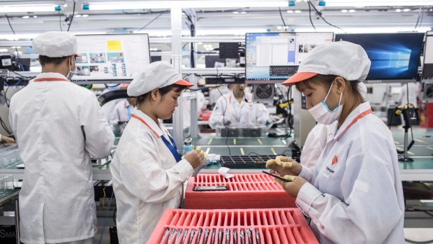 A worker, right, puts a screen protector on a Vsmart smartphone while her colleague, second left, sticks tape to a motherboard on the prodcution line at the VinSmart factory, operated by Vingroup JSC, at Hoa Lac Hi-Tech Park in Hanoi, Vietnam, on Wednesday, Sept. 25, 2019. Vinsmart is the device unit of Vingroup, a cradle-to-grave conglomerate founded by billionaire Pham Nhat Vuong.