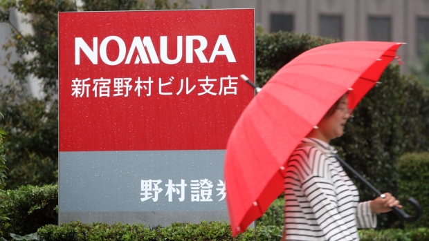 A pedestrian walks past signage for a branch of Nomura Securities Co., a unit of Nomura Holdings Inc., in Tokyo, Japan, on Monday, June 24, 2019. Nomura Holdings shareholders approved the company’s proposals for 10 board members, including Chief Executive Officer Koji Nagai and Chairman Nobuyuki Koga, at their annual meeting in Tokyo Monday. Photographer: Kentaro Takahashi/Bloomberg