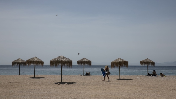 A woman carries a sunbed onto the beach at Glyfada suburb, near Athens, Greece, on Wednesday, May 5, 2021. Tourism is one of the country’s most important industries, accounting for about a fifth of the economy and more than a quarter of jobs. Photographer: Yorgos Karahalis/Bloomberg