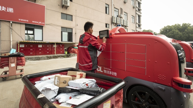 An employee loads packages into a delivery robot at a logistic center during a media tour of JD.com Inc.'s autonomous delivery vehicles in Changshu, Jiangsu province, China, on Thursday, Oct. 22, 2020. JD.com's vast logistics network is set to continue attracting international and domestic brands wanting to deepen their penetration of the Chinese market.