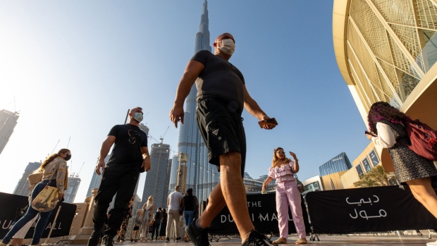 Tourists wearing protective masks walk near the Dubai Mall and the Burj Khalifa skyscraper in Dubai, United Arab Emirates, on Wednesday, Jan. 27, 2021. Dubai replaced its top health official on Sunday after coronavirus cases in the United Arab Emirates, of which it is part, spiked in recent weeks.