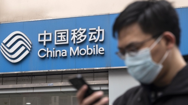 A pedestrian walks past a China Mobile Ltd. store in Shanghai, China, on Wednesday, Jan. 6, 2021. The New York Stock Exchange is considering reversing course a second time to delist three major Chinese telecommunications firms after conferring further with senior authorities on how to interpret an executive order President Donald Trump issued Nov. 12, according to people familiar with the matter. Photographer: Qilai Shen/Bloomberg