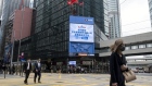 Pedestrians walk across a road past a screen showing a message marking the listing of Baidu Inc. on the Hong Kong Stocks Exchange in Hong Kong, China, on Tuesday, March 23, 2021. Baidu's stock offering in Hong Kong today marks an unlikely resurgence for founder Robin Li, who has fought his way back to relevance in China’s technology industry after squandering a near-monopoly in search. Photographer: Paul Yeung/Bloomberg