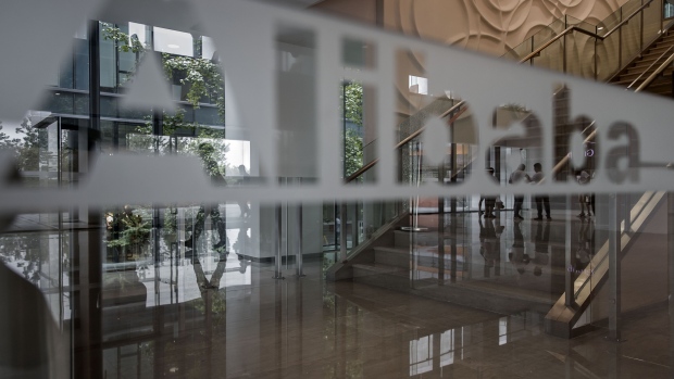 Employees and visitors are reflected on a glass panel at the Alibaba Group Holding Ltd. headquarters in Hangzhou, China, on Friday, Sept. 8, 2017. After conquering grocery deliveries, Alibaba is setting its sights on a new part of China’s $4 trillion retail sector: department stores. Photographer: Qilai Shen/Bloomberg
