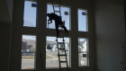 A contractor tapes a window before painting the interior of a house under construction in Lehi, Utah. Photographer: George Frey/Bloomberg