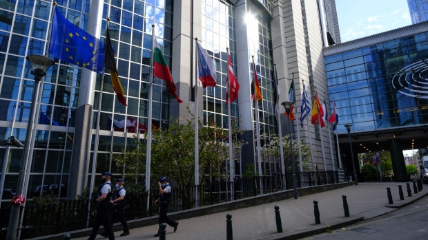 Police patrol near European Union (EU) member state flags outside the European Parliament in Brussels, Belgium, on Tuesday, April 27, 2021. The European Union's post-Brexit trade accord will be instrumental in bolstering the bloc's single market and avoiding a chaotic rupture, Ursula von der Leyen said as lawmakers in Brussels prepared to give the deal their formal approval.