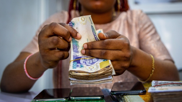 A vendor counts out Nigerian naira banknotes inside a shop at the Ikeja computer village market in Lagos, Nigeria, on Monday, March 29, 2021. Nigerians are having to contend with the highest inflation rate in four years, the second-highest unemployment rate on a list of 82 countries tracked by Bloomberg, and an economy that’s only just emerged from recession. Photographer: Adetona Omokanye/Bloomberg
