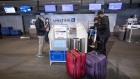 Travelers wearing protective masks use automated kiosks at the United Airlines check-in area at San Francisco International Airport.