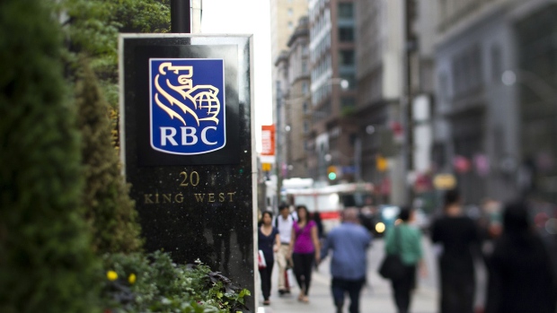 Pedestrians pass in front of RBC Royal Bank signage outside the company's office in this photo taken with a tilt-shift lens near Bay Street in Toronto.