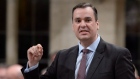 Industry Minister James Moore answers a question during Question Period