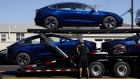 Workers unload Tesla Model 3 electric vehicles from a car carrier outside the company's delivery center in Marina Del Rey, California. Photographer: Patrick T. Fallon/Bloomberg