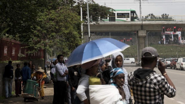 Pedestrians queue for a bus near an Addis Ababa light rail station in Addis Ababa, Ethiopia.