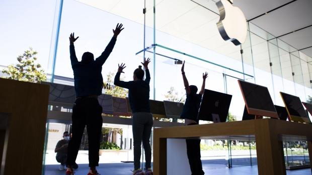 Apple employees jump for a photo behind the new Apple Inc. iMac computers on display at an Apple store in Palo Alto, California, U.S., on Friday, May 21, 2021. Apple Inc. rolled out the first redesign of its flagship desktop iMac computer in almost a decade, showcasing its latest machine with in-house designed chips instead of those made by Intel Corp.