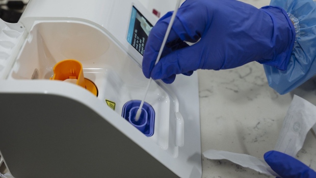 A healthcare worker wearing protective gloves places a swab in an Abbott Laboratories ID NOW rapid test machine during a United Airlines Covid-19 test pilot program at Newark Liberty International Airport in Newark, New Jersey, U.S., on Monday, Nov. 16, 2020. From November 16 through December 11, the United Airlines will offer rapid tests to every passenger over 2 years old and crew members on board select flights from Newark Liberty International Airport to London Heathrow, free of charge. Photographer: Angus Mordant/Bloomberg