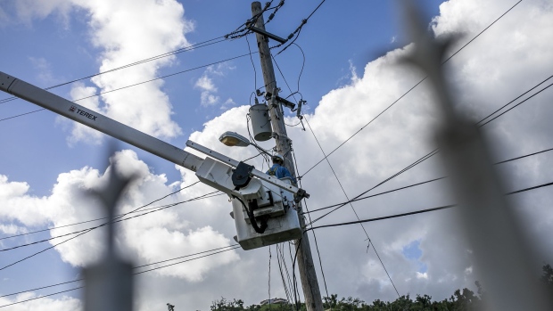 A worker stands in a cherry picker while fixing power lines on a utility pole in the town of Limones, Yabucoa, Puerto Rico.