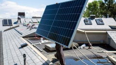 A worker moves a solar panel into position on a roof during a Shift Energy Group solar installation on a home in Victoria, British Columbia, Canada, on Tuesday, May 18, 2021. Last December, the Trudeau government outlined the steps Canada would need to take to reach net-zero carbon emissions by 2050, including government grants for homeowners for energy retrofits and a need for rooftop solar installers, CBC News reported. Photographer: James MacDonald/Bloomberg