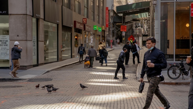 Pedestrians walk along a street in the Financial District of New York, U.S., on Wednesday, May 12, 2021. With 37% of Manhattan fully vaccinated, the city's finance industry, slowly, is getting back into the office. Photographer: Amir Hamja/Bloomberg