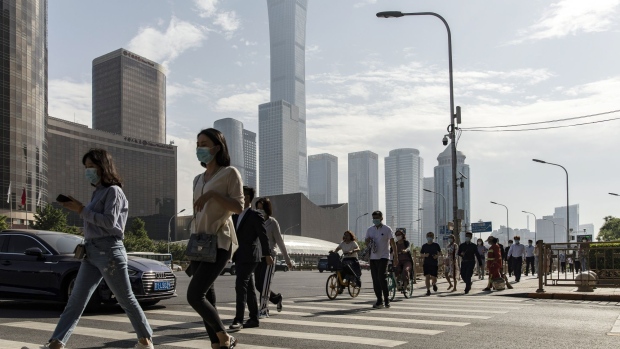 Pedestrians wearing protective masks walk across a road in the central business district in Beijing, China, on Thursday, May 27, 2021. China signaled the yuan's recent appreciation, which has taken it to a three-year high against the dollar, is too rapid with a weaker-than-expected reference rate. Photographer: Qilai Shen/Bloomberg