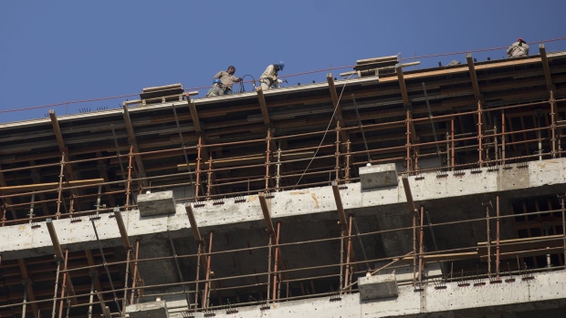 Laborers work on the upper level of a tower block under construction in Dhahran, Saudi Arabia, on Thursday, Oct. 4, 2018. Saudi Arabia's Crown Prince Mohammed said the central elements of his Vision 2030 plan, including the $100 billion Saudi Aramco sale and the effort to boost non-oil revenue, remain on course. Photographer: Simon Dawson/Bloomberg