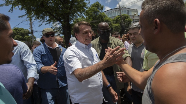 Jair Bolsonaro, Brazil's president, center, greets an attendee after casting his vote during the second round of the municipal elections in Rio de Janeiro, Brazil, on Sunday, Nov. 29, 2020. Bolsonaro is following the advice of his closest advisers to remain discreet and not support any candidates in the second round, after most of the candidates he backed in the first round were defeated.