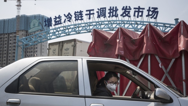 A woman wearing a protective mask sits in her car at the Baishazhou wet market in Wuhan, Hubei Province, China, on Monday, April 6, 2020. The Chinese city where the coronavirus first emerged has stirred back to life following a lockdown lasting for months.