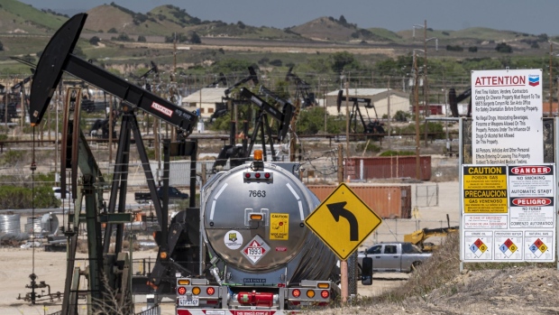A tanker truck drives past oil well pump jacks operated by Chevron Corp. in San Ardo, California, U.S., on Tuesday, April 27, 2021. Oil climbed by the most in nearly two weeks with the OPEC+ alliance and BP pointing to signs of a robust demand recovery taking shape in parts of the world. Photographer: David Paul Morris/Bloomberg