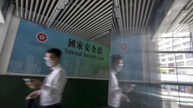 A pedestrian wearing a protective mask walks past a government-sponsored advertisement promoting a new national security law in Hong Kong, China, on Monday, June 29, 2020. The national security law that China could impose on Hong Kong as early as this week won't need to be used if the financial hub's residents avoid crossing certain "red lines," according to Bernard Chan, a top adviser to Hong Kong Chief Executive Carrie Lam. Photographer: Paul Yeung/Bloomberg