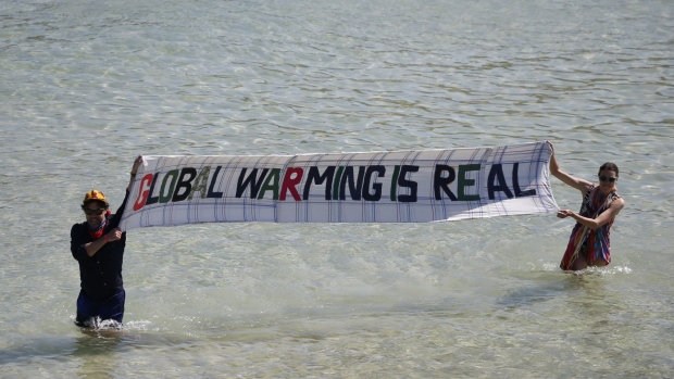 Extinction Rebellion protesters hold a sign that says "Global Warming is Real" in the sea on the sidelines of the final day of the Group of Seven leaders summit, in St. Ives, U.K., on Sunday, June 13, 2021. The worlds richest governments are under mounting pressure to help poor countries fight climate change. Photographer: Hollie Adams/Bloomberg