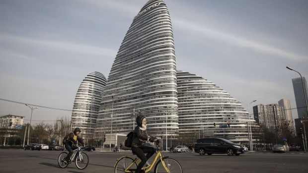 Commuters ride bicycles past commercial buildings at the Soho China Ltd. Wangjing Soho project in Beijing, China, on Friday, Nov. 25, 2016. China's economy remains steady this month even amid efforts to cool property markets, according to some of the earliest private economic indicators.