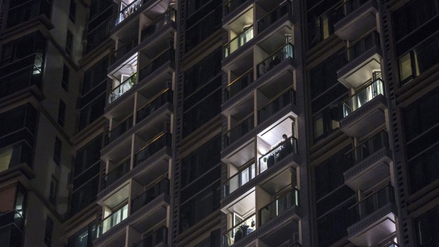 A resident looks out from their balcony of a residential building in an area under lockdown on Pok Fu Lam Road in the Sai Ying Pun neighborhood of Hong Kong, China, on Sunday, March 14, 2021. Hong Kong sent hundreds of people, including a playgroup of infants, into quarantine and ordered compulsory testing at 150 locations as it tried to contain a coronavirus outbreak that began in a gym in the city center last week. Photographer: Jusitn Chin/Bloomberg